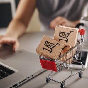 Online shopping . ecommerce and delivery service concept : Paper cartons with a cart or trolley logo on a laptop keyboard, depicts customers order things from retailer sites via the internet.
